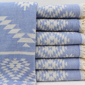 Peut inclure: Une pile de six serviettes turques bleu clair avec un motif g&eacute;om&eacute;trique blanc et des bords frang&eacute;s.