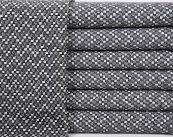 May include: A stack of eight gray and white checkered kitchen towels. The towels are folded and stacked neatly.
