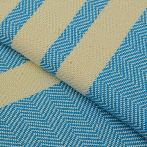May include: A close-up of a white and blue striped fabric with a chevron pattern. The fabric is soft and textured.
