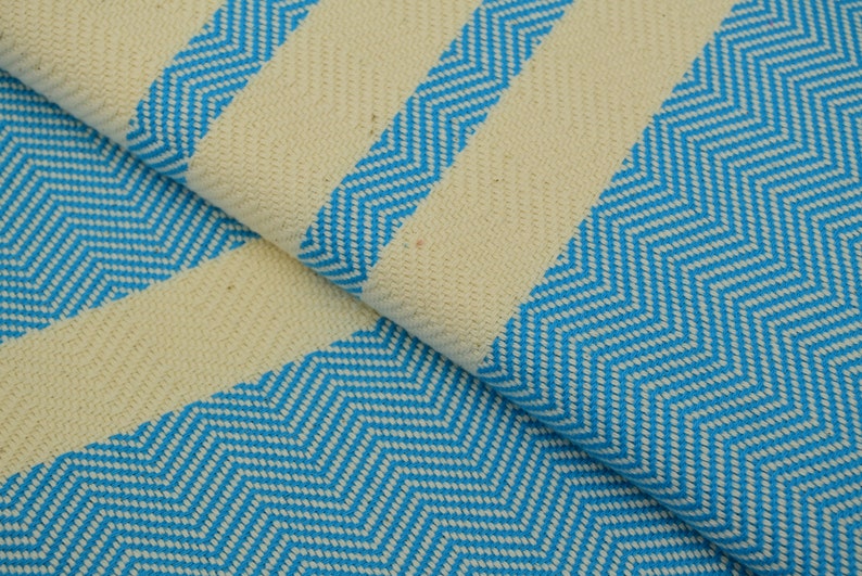 May include: A close-up of a white and blue striped fabric with a chevron pattern. The fabric is soft and textured.