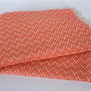 May include: Orange and white checkered throw blanket with a fringe border.