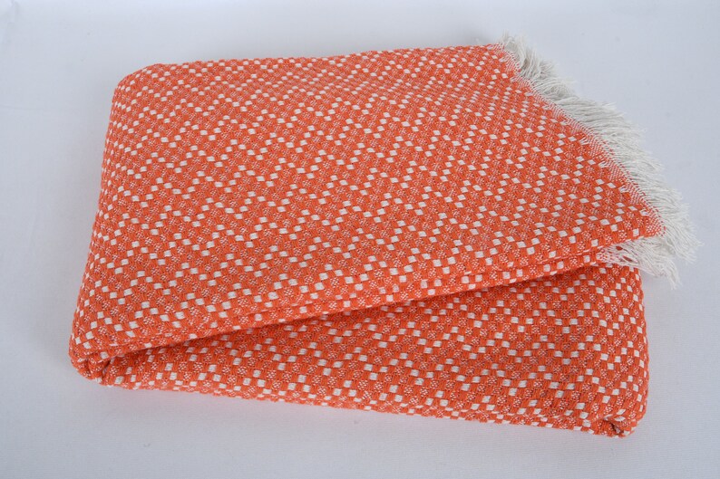 May include: Orange and white checkered throw blanket with a fringe border.