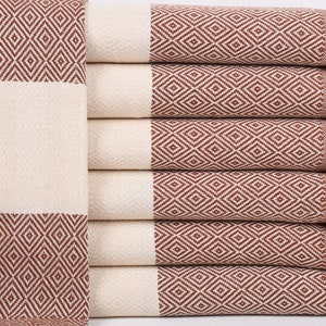 May include: A stack of brown and white striped towels with fringe edges. The towels have a diamond pattern.
