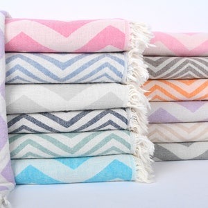 Puede incluir: Una pila de toallas coloridas con un patrón de chevron. Las toallas están dobladas y dispuestas en una fila. Las toallas están hechas de algodón y tienen una textura suave y absorbente.