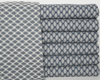 May include: A stack of eight blue and white patterned throw blankets. The blankets are folded and stacked on top of each other.