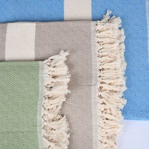 May include: Three striped towels with fringe. The towels are in shades of green, brown, and blue. Each towel has a diamond pattern.