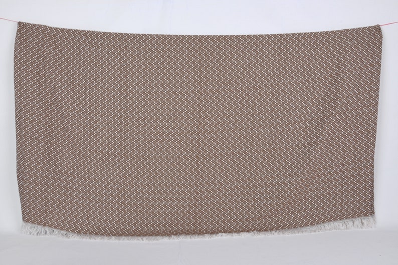 May include: A brown and white patterned throw blanket with a fringed edge.