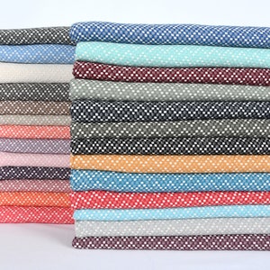 May include: A stack of 20 different patterned fabrics in various colors, including blue, green, red, orange, and brown. The fabrics have a small, white, geometric pattern.