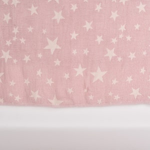 Pode incluir: Uma toalha rosa com um padrão de estrelas brancas.
