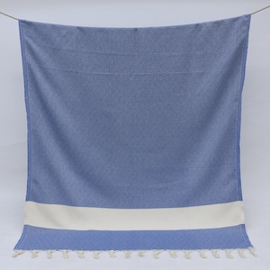 May include: A blue and white Turkish towel with a white stripe and fringe.