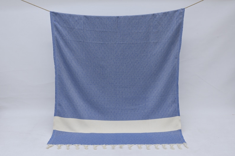 May include: A blue and white Turkish towel with a white stripe and fringe.