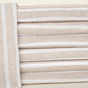 May include: A stack of six beige and white striped towels. The towels are folded and stacked neatly.