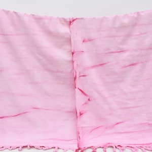 May include: A pink and red striped cotton throw blanket with fringe on the bottom edge.