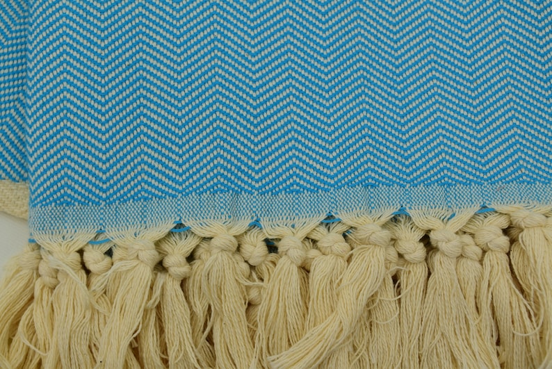 May include: A blue and white patterned Turkish towel with a fringe border. The towel is made of cotton and has a soft, absorbent texture.