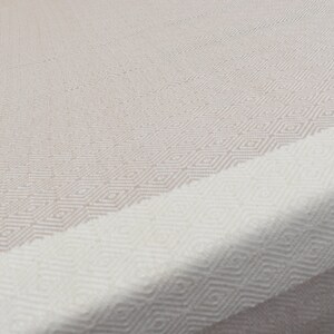 May include: A white and beige woven throw blanket with a diamond pattern.