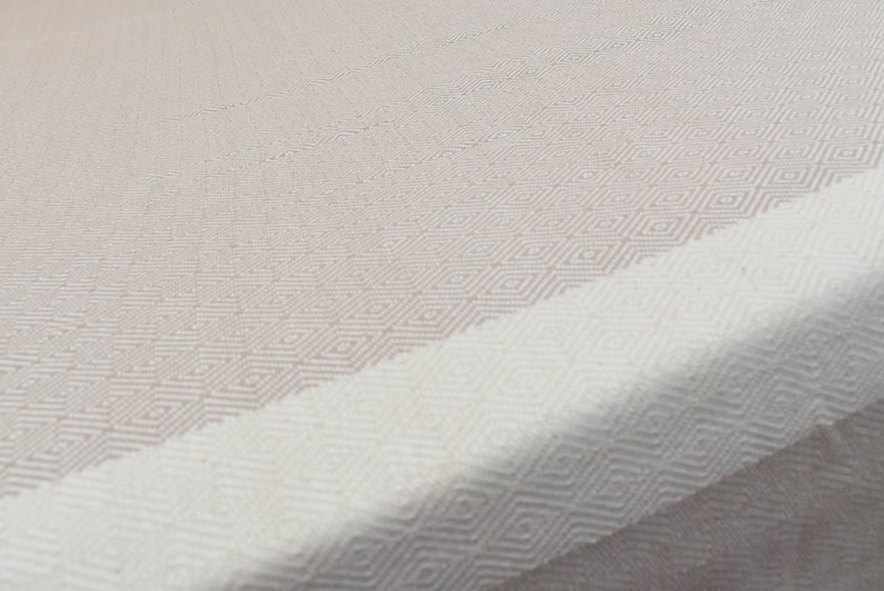 May include: A white and beige woven throw blanket with a diamond pattern.