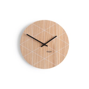 Puede incluir: Un reloj de madera redondo con un patr&oacute;n geom&eacute;trico blanco y agujas negras. La esfera del reloj tiene el texto "UPSTAIRS" impreso.