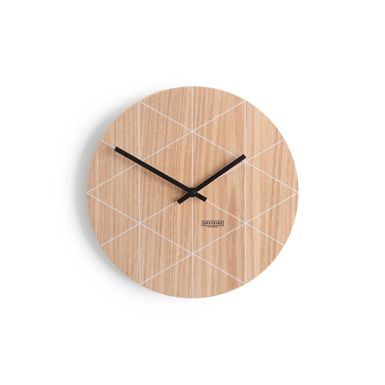 Puede incluir: Un reloj de madera redondo con un patr&oacute;n geom&eacute;trico blanco y agujas negras. La esfera del reloj tiene el texto "UPSTAIRS" impreso.
