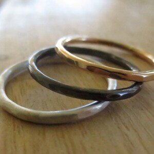 May include: Three simple bands stacked together. The top band is gold, the middle band is black, and the bottom band is silver.