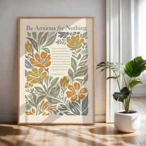 May include: A rectangular wall art print featuring the text Be Anxious for Nothing and Philippians 4:6-7 in a serif font. The design is surrounded by a botanical illustration of stylised flowers and leaves in shades of mustard yellow and grey.