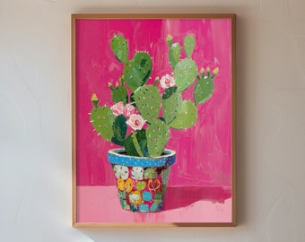 May include: A painting of a potted cactus with pink flowers on a bright pink background. The cactus is in a colorful, patterned pot. The painting is framed in a light wood frame.