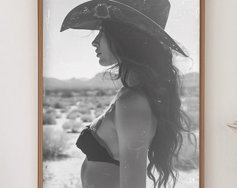 May include: A black and white framed print of a person wearing a cowboy hat and bikini top, set against a desert landscape. The print hangs on a white wall above a wooden console table. A woven basket and rug are in front of the table.