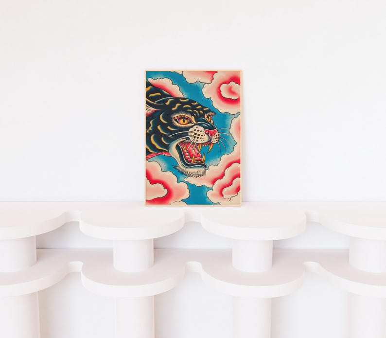 May include: A rectangular art print featuring a black panther head with yellow eyes and an open mouth showing sharp teeth. The panther is surrounded by stylized pink clouds against a bright blue background, all enclosed in a thin wooden frame.
