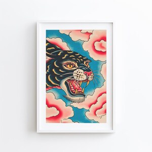 May include: A framed art print featuring a black panther with yellow eyes and an open mouth showing sharp teeth. The panther is surrounded by stylized pink and cream-colored clouds against a vibrant blue background, rendered in a bold graphic style.