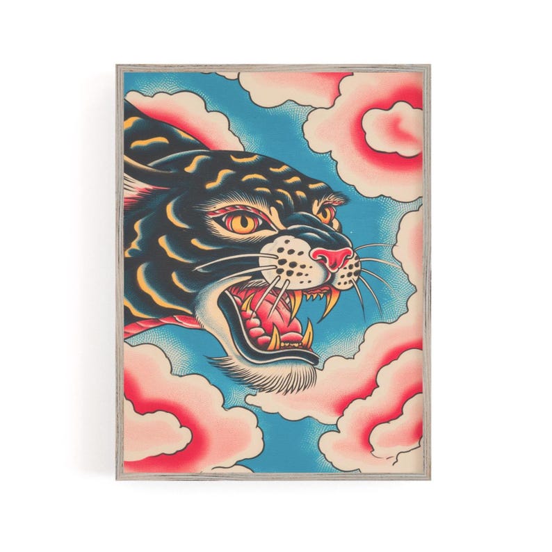 May include: A framed art print featuring a stylized black panther head with yellow eyes and an open mouth showing teeth, set against a blue background with pink and white clouds. The illustration uses bold lines and a vibrant color palette.