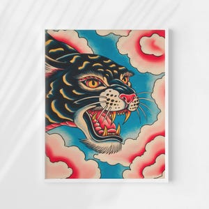 May include: A rectangular art print featuring a stylized black panther head with yellow eyes and an open mouth showing sharp teeth. The panther is surrounded by pink, cloud-like shapes against a textured blue background, all within a white frame.