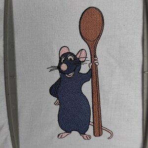 Puede incluir: Dise&ntilde;o bordado de una rata de dibujos animados sosteniendo una cuchara de madera. La rata es azul con orejas y nariz rosadas. La cuchara es marr&oacute;n.