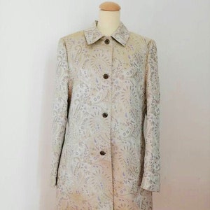 May include: A long-sleeved, button-up coat with a paisley pattern in shades of beige, silver, and purple.
