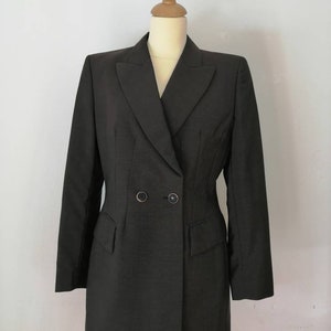 Può includere: Un blazer grigio scuro doppiopetto con collo a revers e maniche lunghe.
