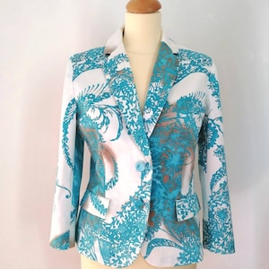 May include: A white blazer with a teal floral pattern. The blazer has a single button closure and a pocket on the left side.