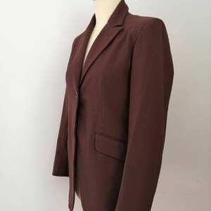 Pu&ograve; includere: Un blazer marrone con un solo bottone di chiusura e un colletto a punta.