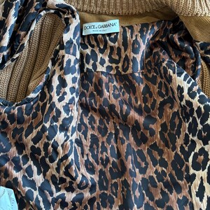 May include: A brown and black leopard print fabric with a label that reads "Dolce & Gabbana" and "Made in Italy".