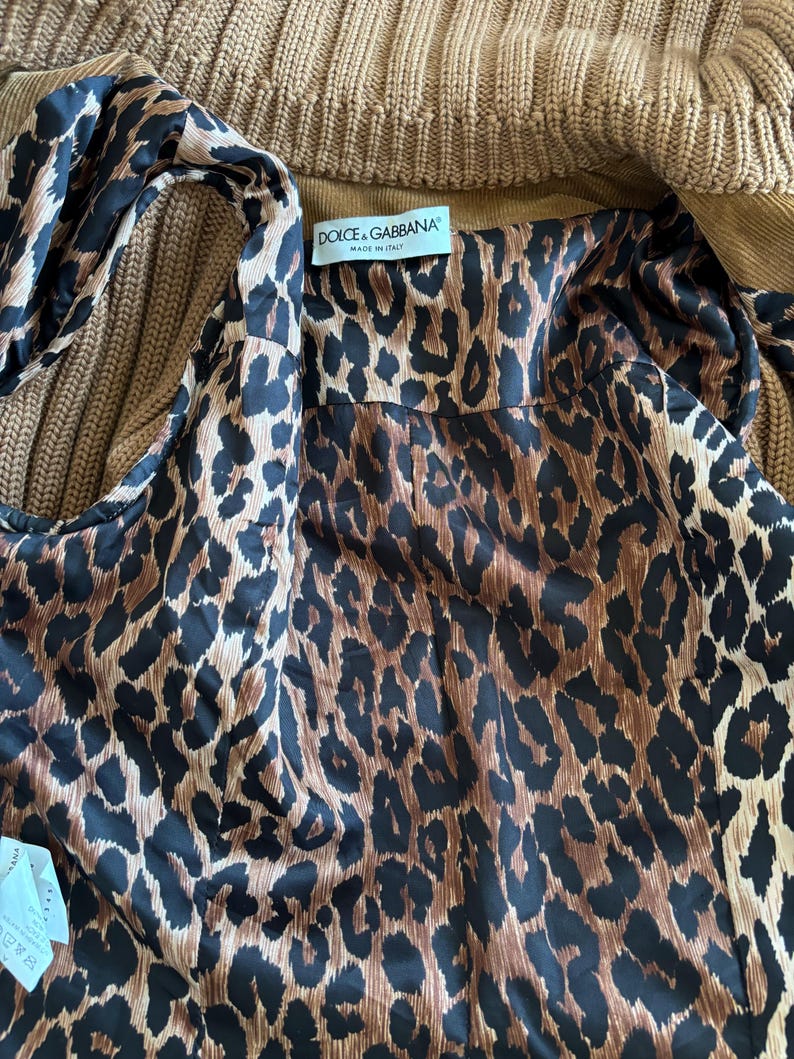 May include: A brown and black leopard print fabric with a label that reads "Dolce & Gabbana" and "Made in Italy".