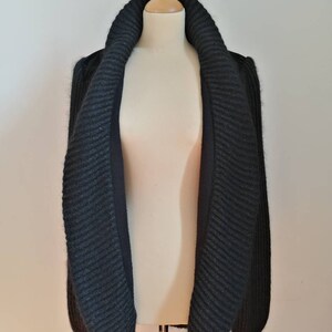 May include: A black knitted cardigan with a large, folded collar. The cardigan is made of a soft, textured yarn and has a relaxed fit.