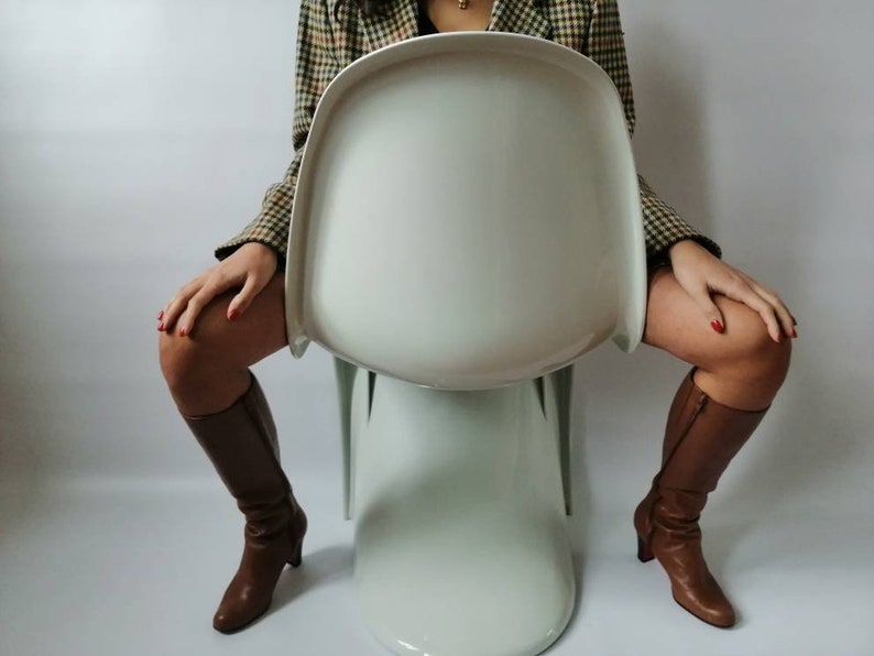 May include: A white, modern, sculptural chair with a rounded back and a wide, flat seat. The chair is made of a smooth, glossy material and has a unique, organic shape.