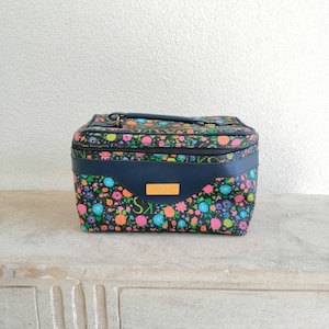 May include: A black and blue floral print cosmetic bag with a gold zipper and handle.