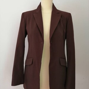 Pu&ograve; includere: Un blazer marrone con un solo bottone di chiusura e maniche lunghe. Il blazer ha una vestibilit&agrave; classica e aderente.