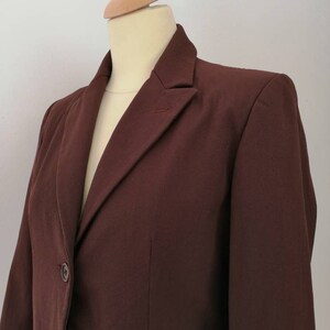 Pu&ograve; includere: Un blazer marrone con un solo bottone di chiusura e un colletto a punta.