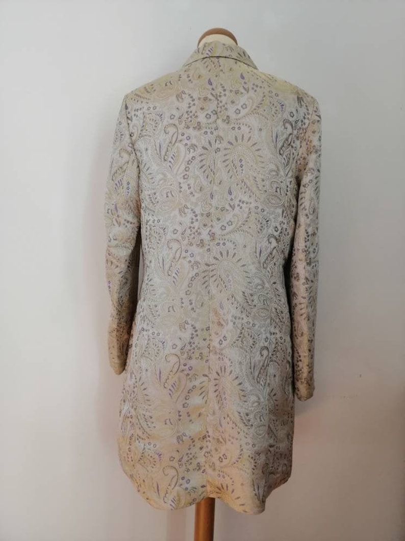 May include: A long-sleeved jacket with a paisley pattern in shades of gold, purple, and white.