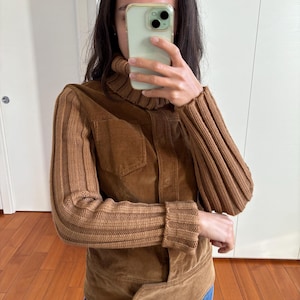 May include: A brown corduroy jacket with knitted sleeves. The jacket has a high collar and a button closure.