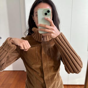 May include: A brown corduroy jacket with a high collar and ribbed knit sleeves. The jacket has a button closure and two pockets.