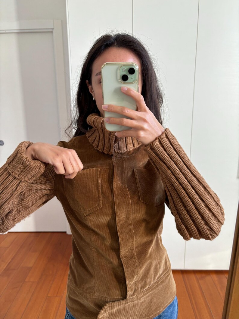 May include: A brown corduroy jacket with a high collar and ribbed knit sleeves. The jacket has a button closure and two pockets.