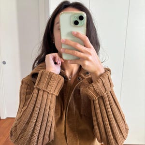 May include: A brown corduroy jacket with a zipper closure and ribbed knit sleeves. The jacket has a stand-up collar and two pockets on the front.