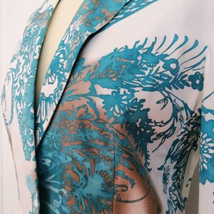 May include: A white blazer with a teal and brown floral pattern. The blazer has a notched collar and a single button closure.