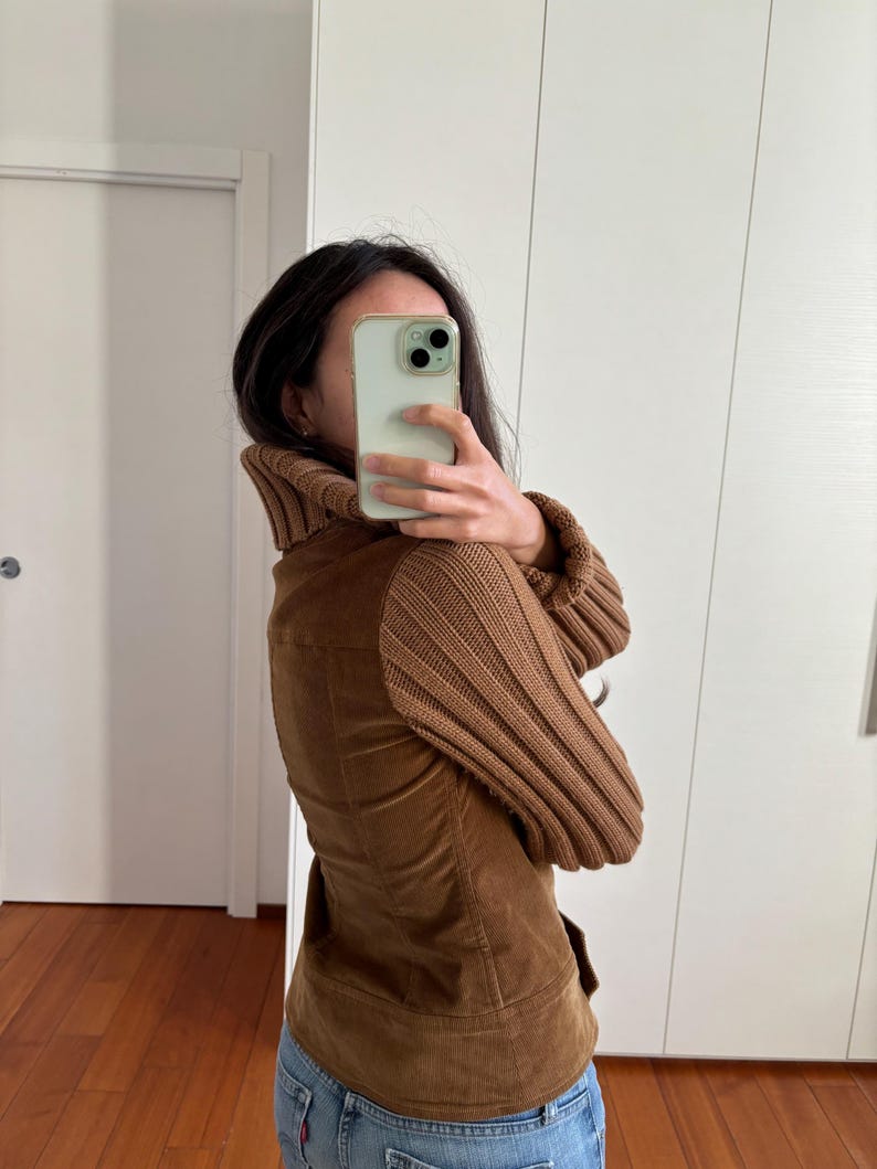 May include: A brown corduroy jacket with a brown knit turtleneck collar and brown knit sleeves. The jacket has a fitted silhouette and a zipper closure.