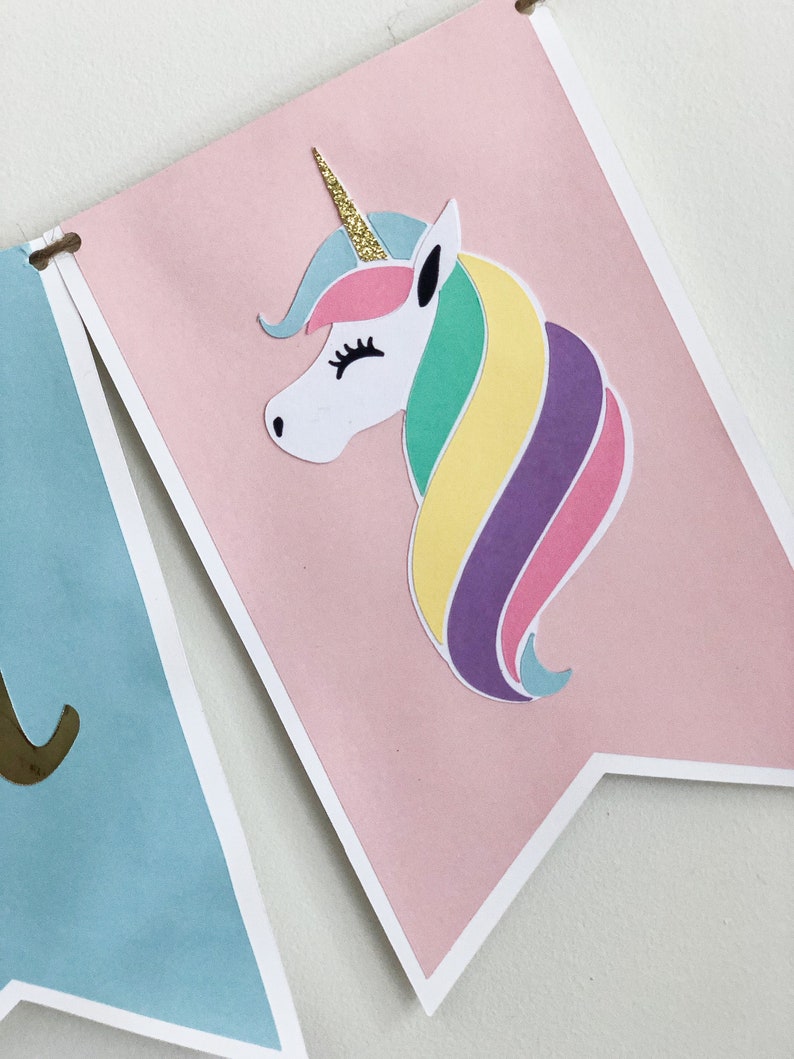 Puede incluir: Una pancarta rosa con un unicornio blanco con un cuerno de purpurina dorada y una crin arco&iacute;ris. El unicornio est&aacute; sobre un fondo rosa con un borde blanco.